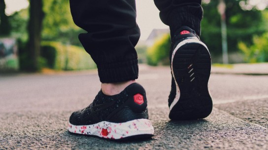 persoon in zwarte sneakers lopen op straat (vergroot foto)